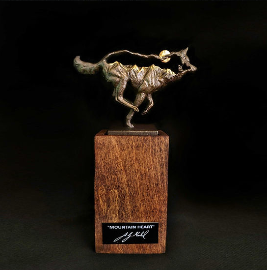 Bronze sculpture of a running wolf on a wooden block. Shadow on the stone background.