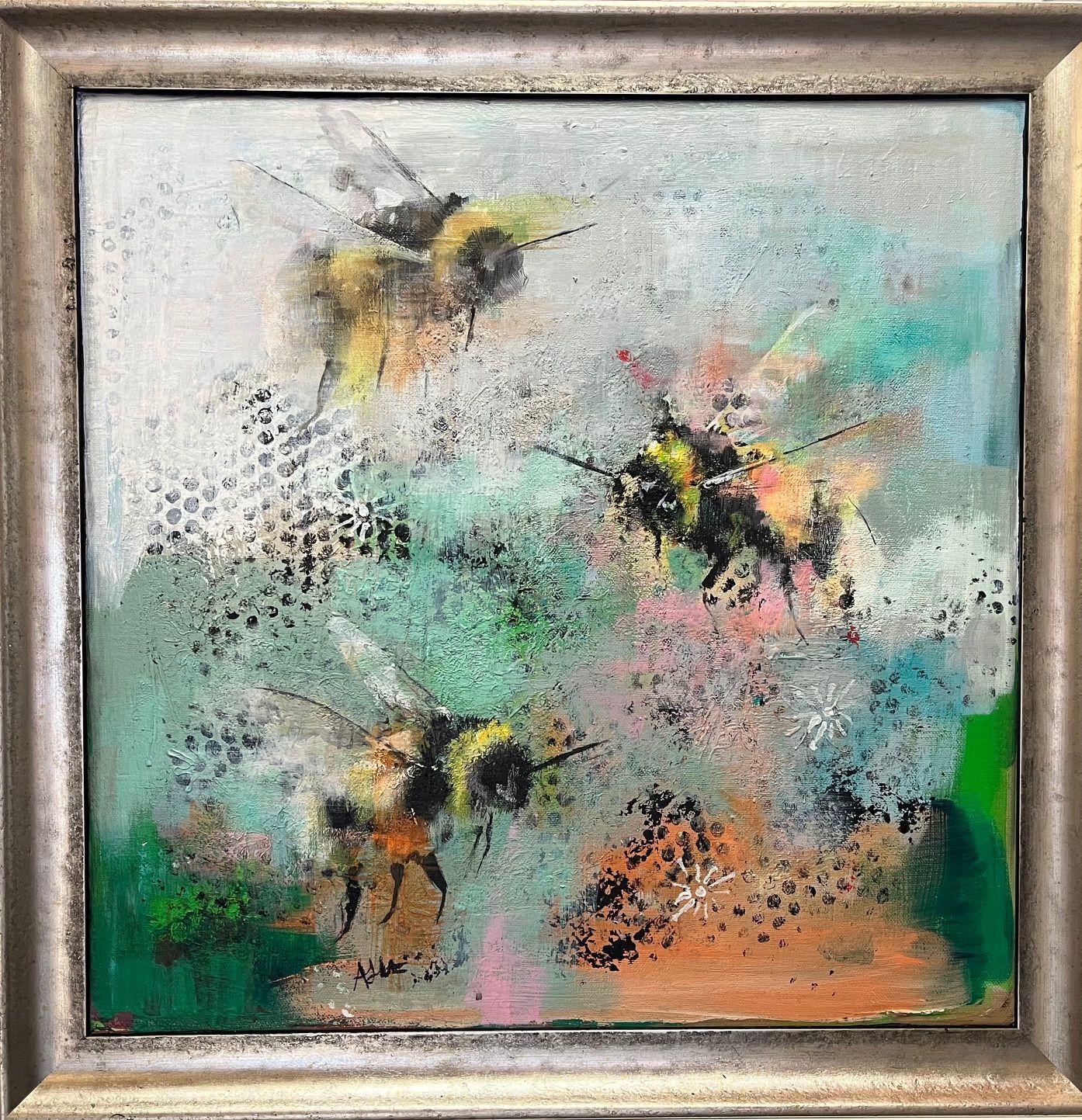 Abstract painting of three bees over green, yellow, pink, and orange textured background in a framed canvas