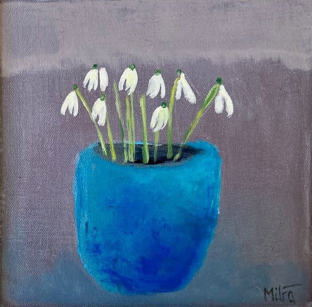 Blue vase of white snowdrop flowers against a grey background.