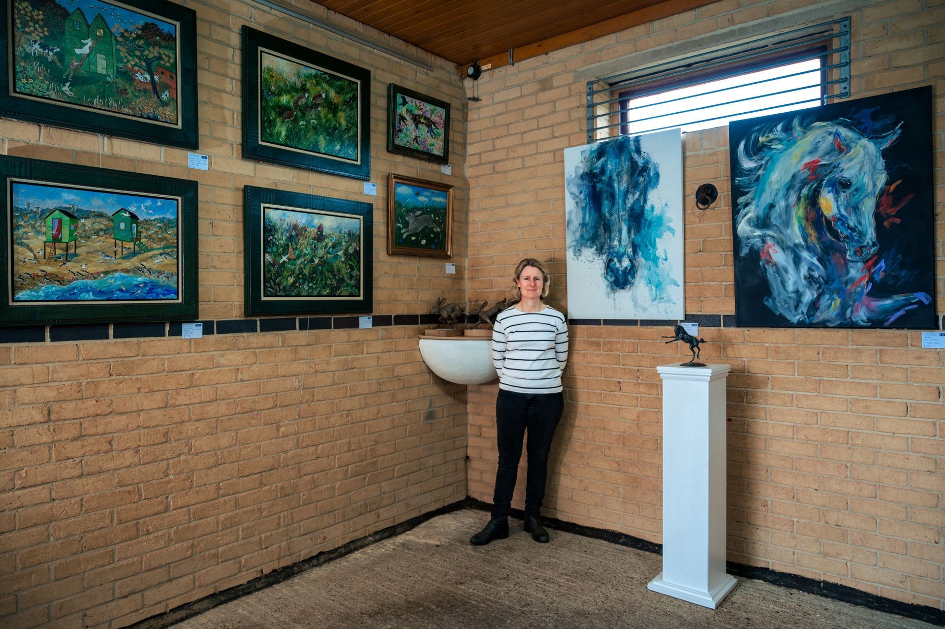 A woman is standing in a room with paintings on the wall.