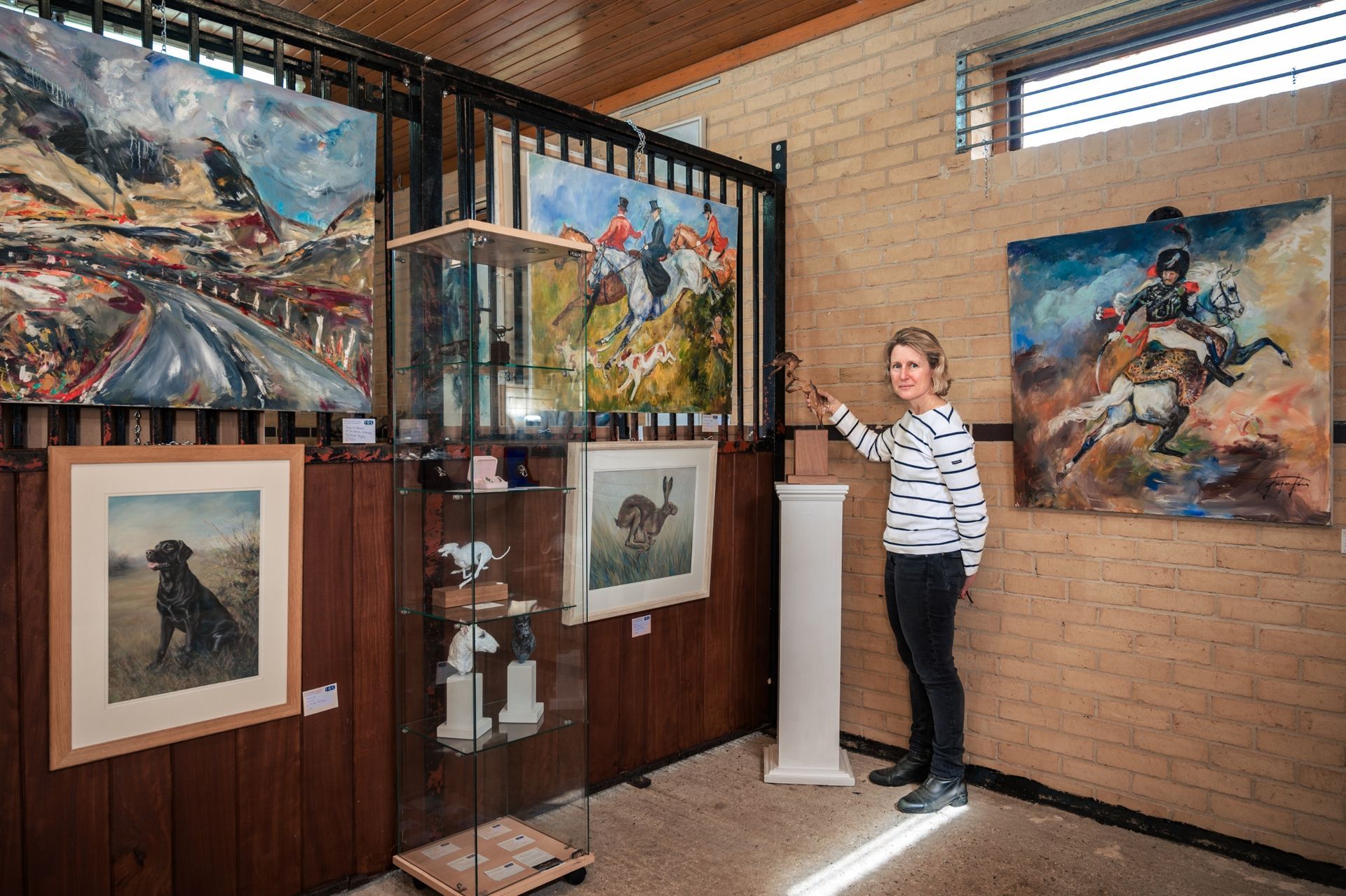A woman is standing in a room with paintings on the wall.