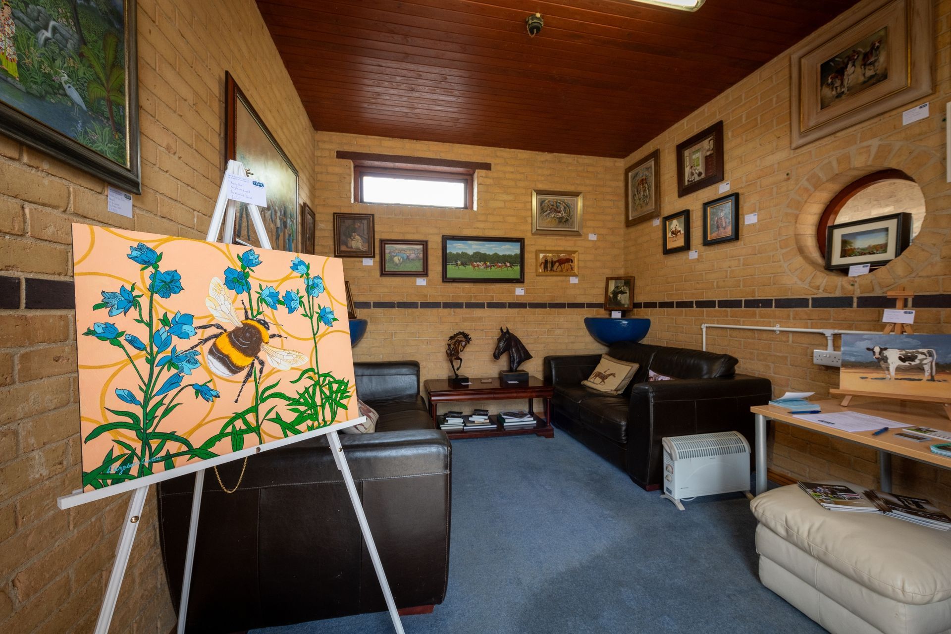 A living room with a painting of a bee on an easel.