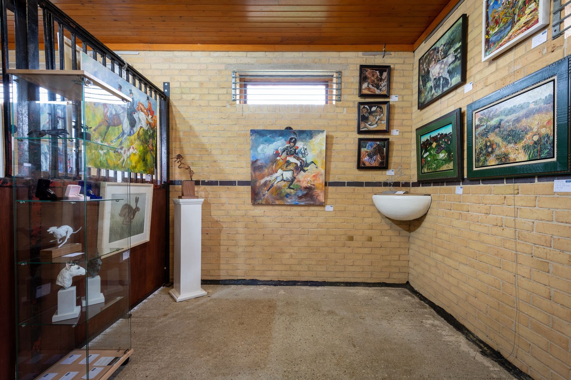 A room with a lot of paintings on the walls and a sink.