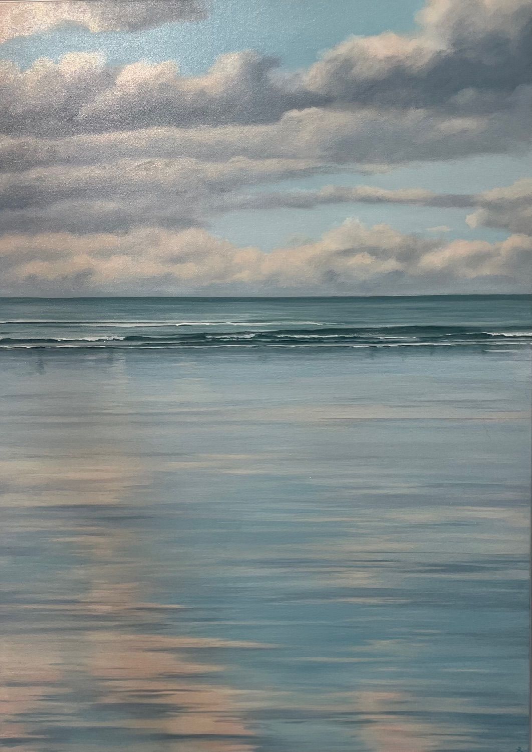 Calm ocean reflecting cloudy sky; blues and whites dominate the scene.