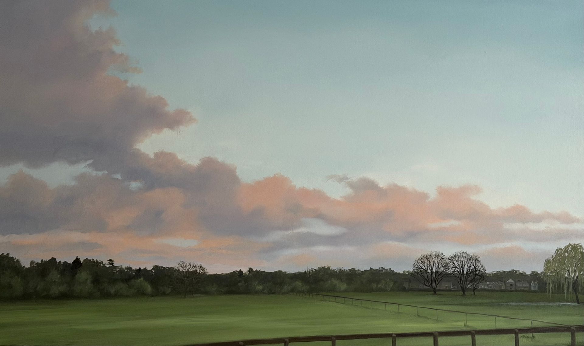 Pastel sky over a green field with trees and a wooden fence.