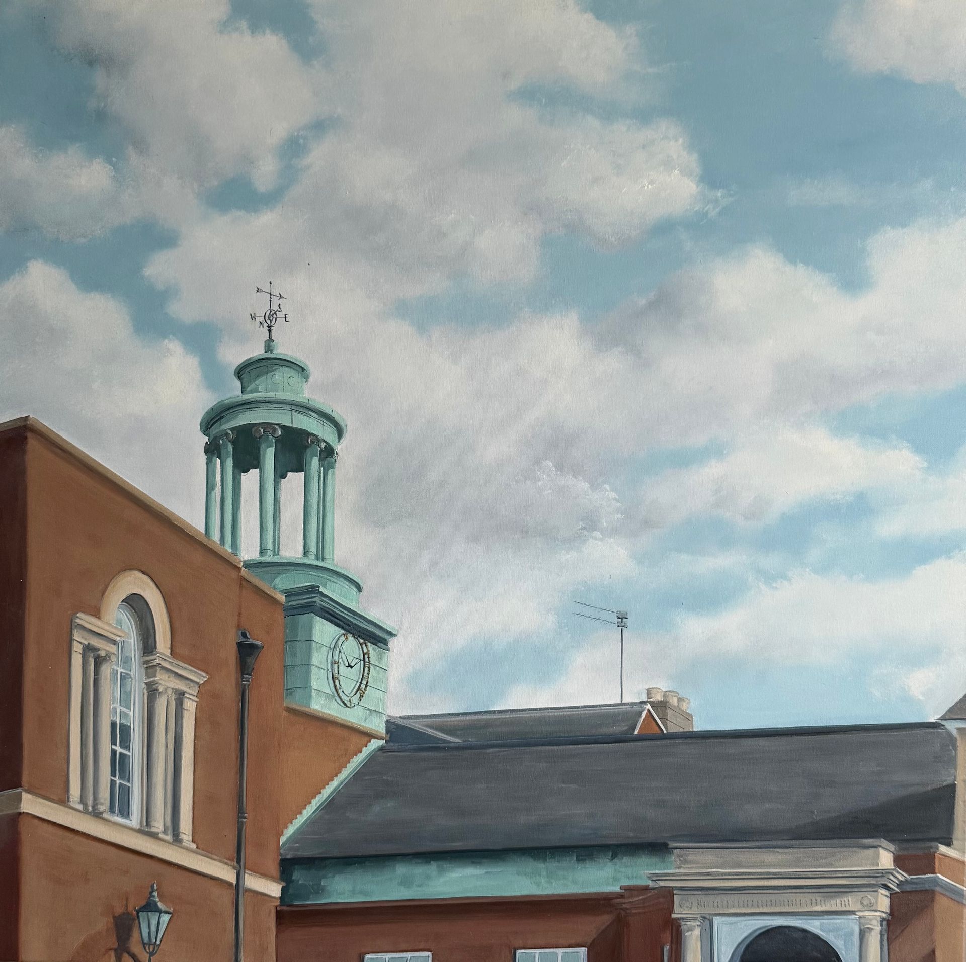 Red brick building with a turquoise clock tower against a cloudy sky.