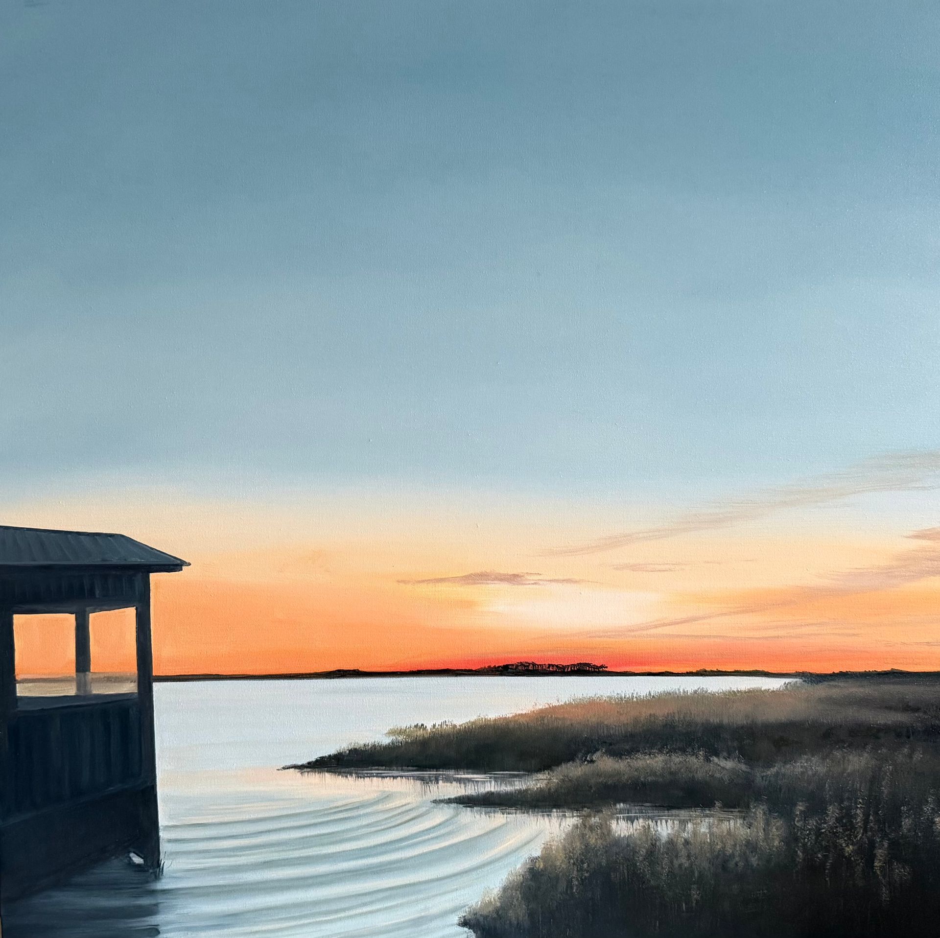 Sunset over water, a small dock on the left, grassy marsh on the right. Orange and blue sky.