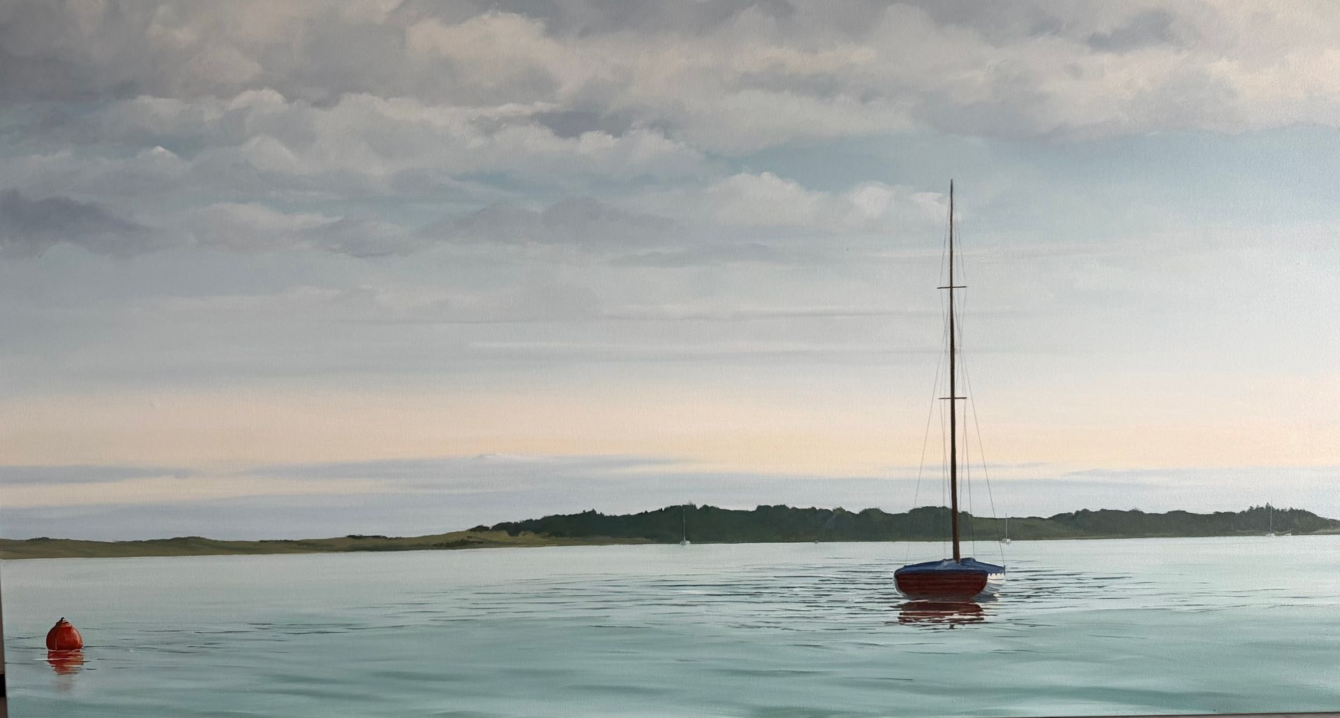 Sailboat on calm water near a small island, under a cloudy sky.