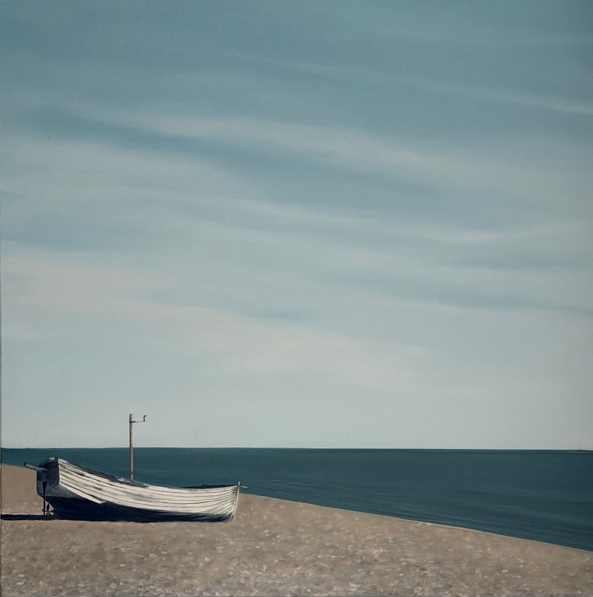 White boat on a pebble beach with a blue sky and ocean in the background.
