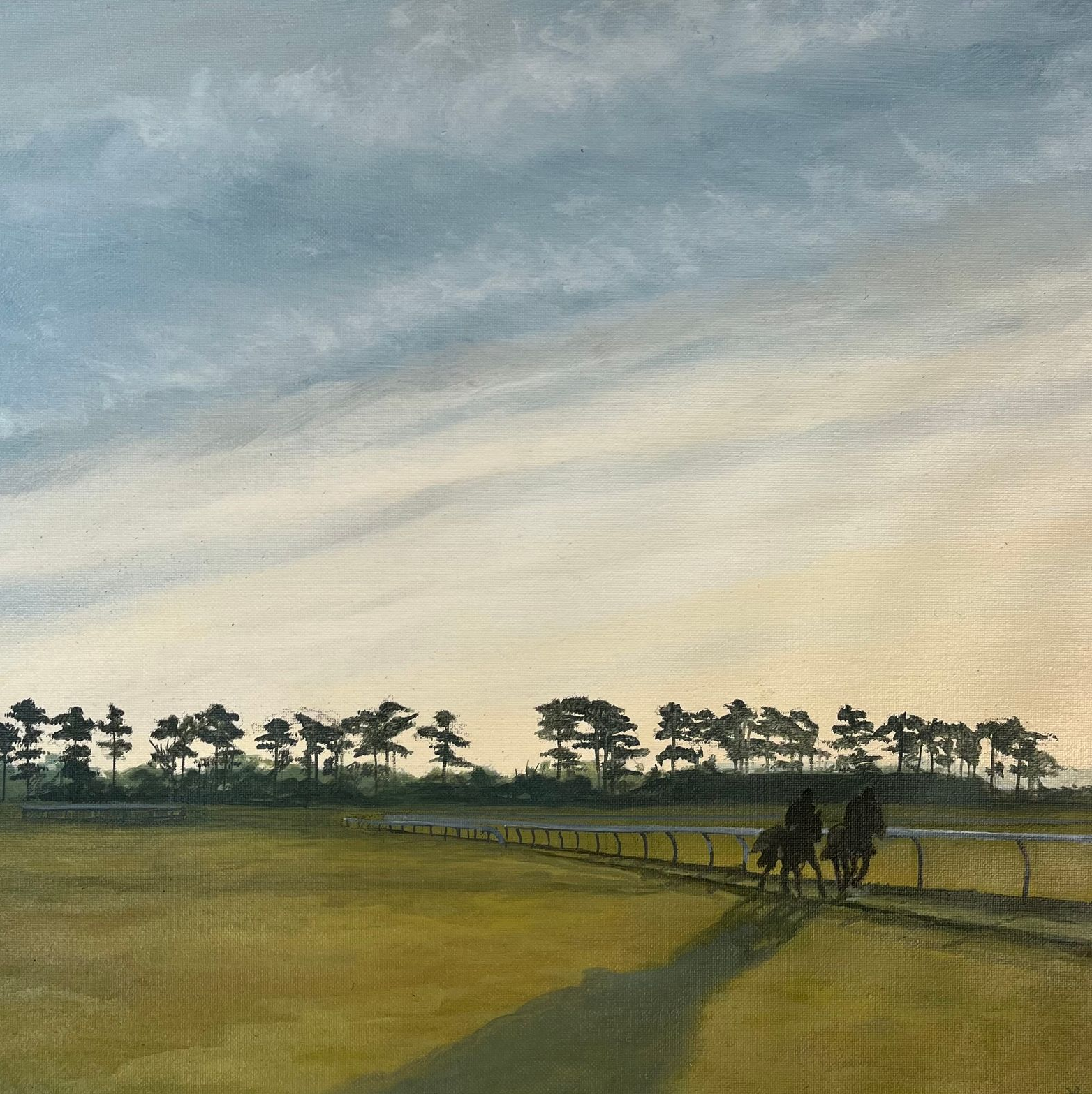 Two horses and riders on a race track at sunset, with trees on the horizon and a cloudy sky.