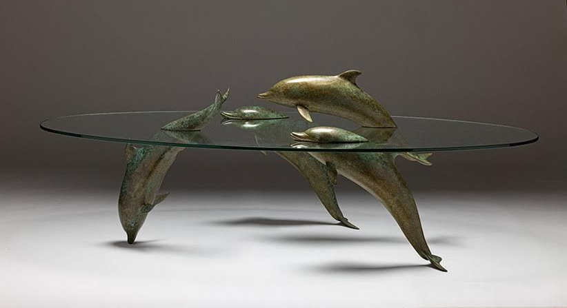 Bronze dolphin table with glass top. Dolphins form legs and support tabletop.