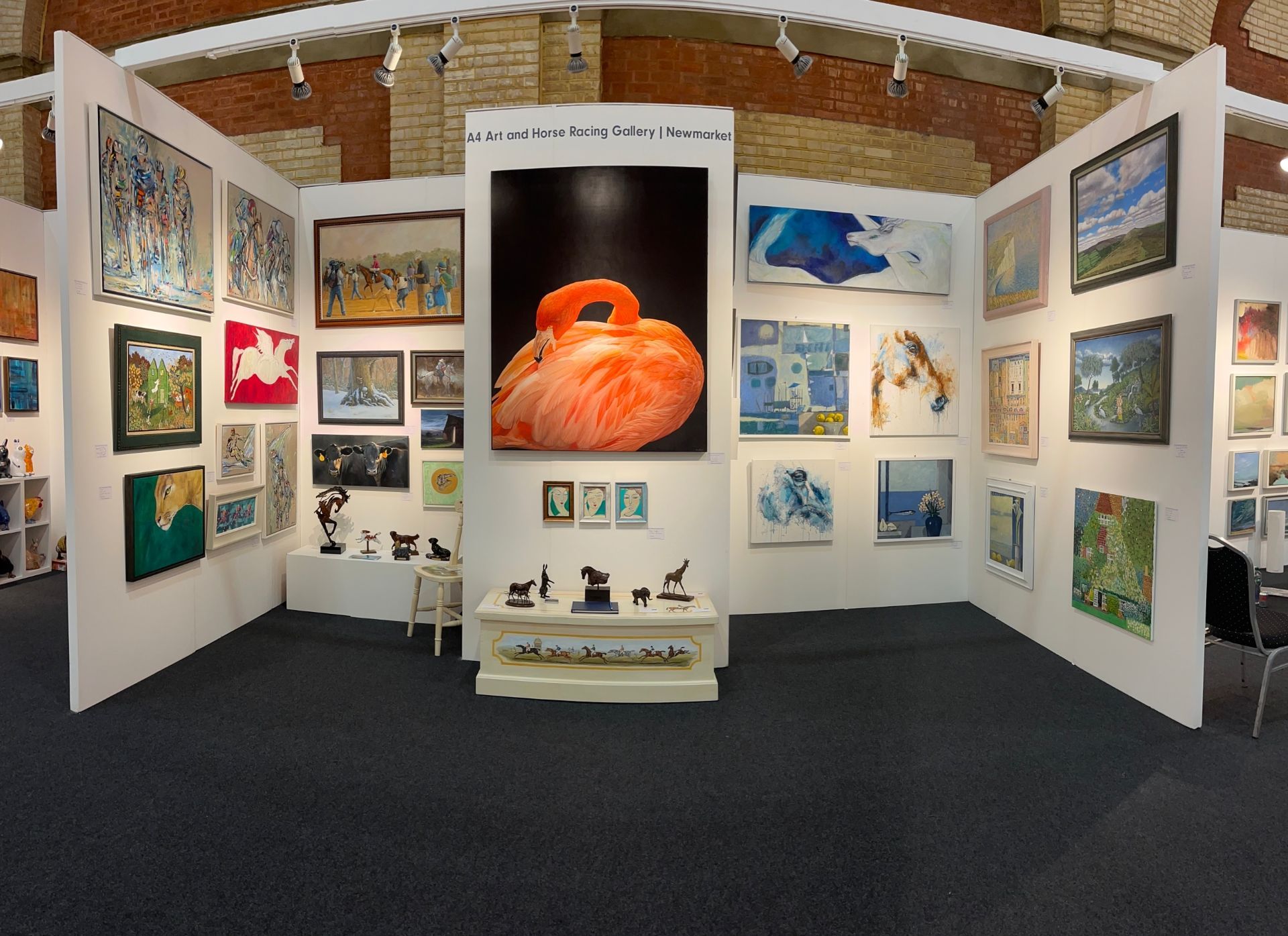 Art exhibition with paintings on white walls. A large, orange art piece is centered.
