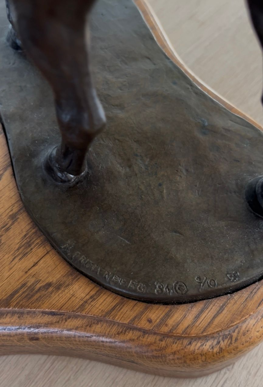Bronze sculpture base with inscription and wooden stand.