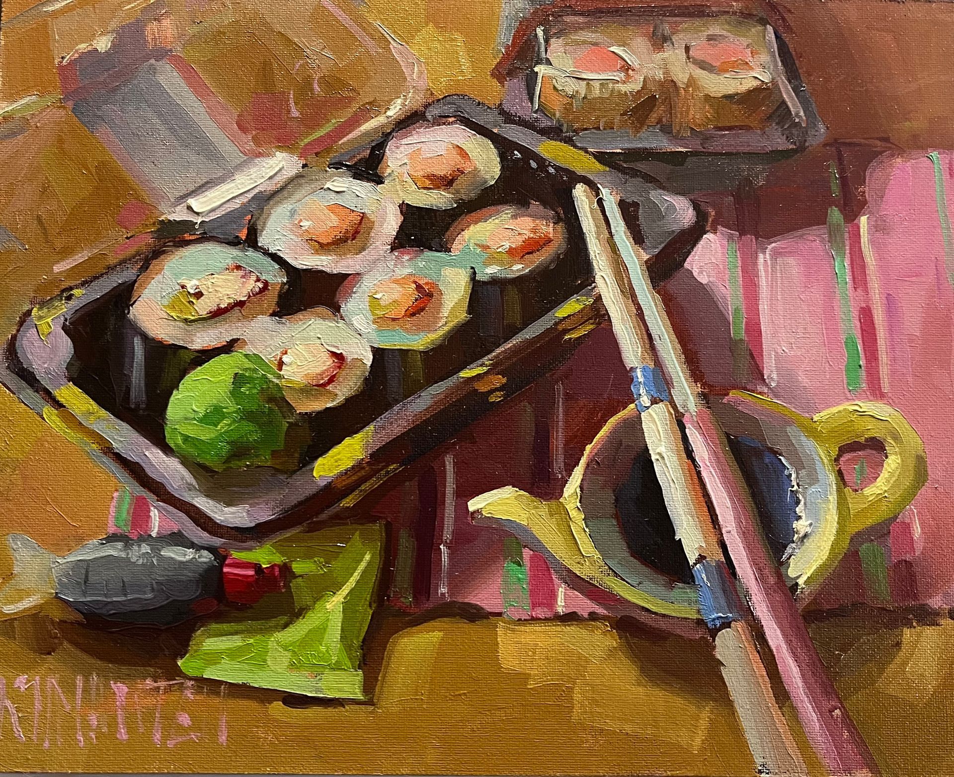 Sushi rolls in black trays with chopsticks and a tea cup on a pink-striped cloth.