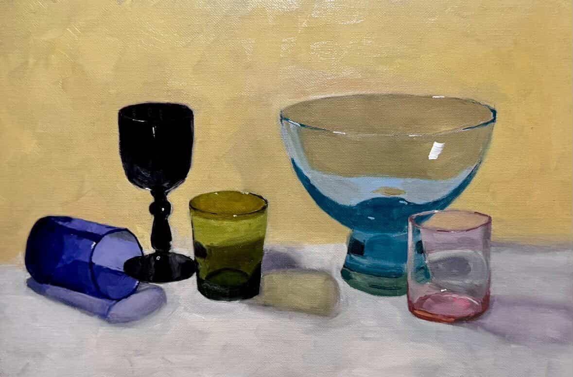 Assorted colorful glassware on a tabletop, including bowls and tumblers, painted in soft pastel tones