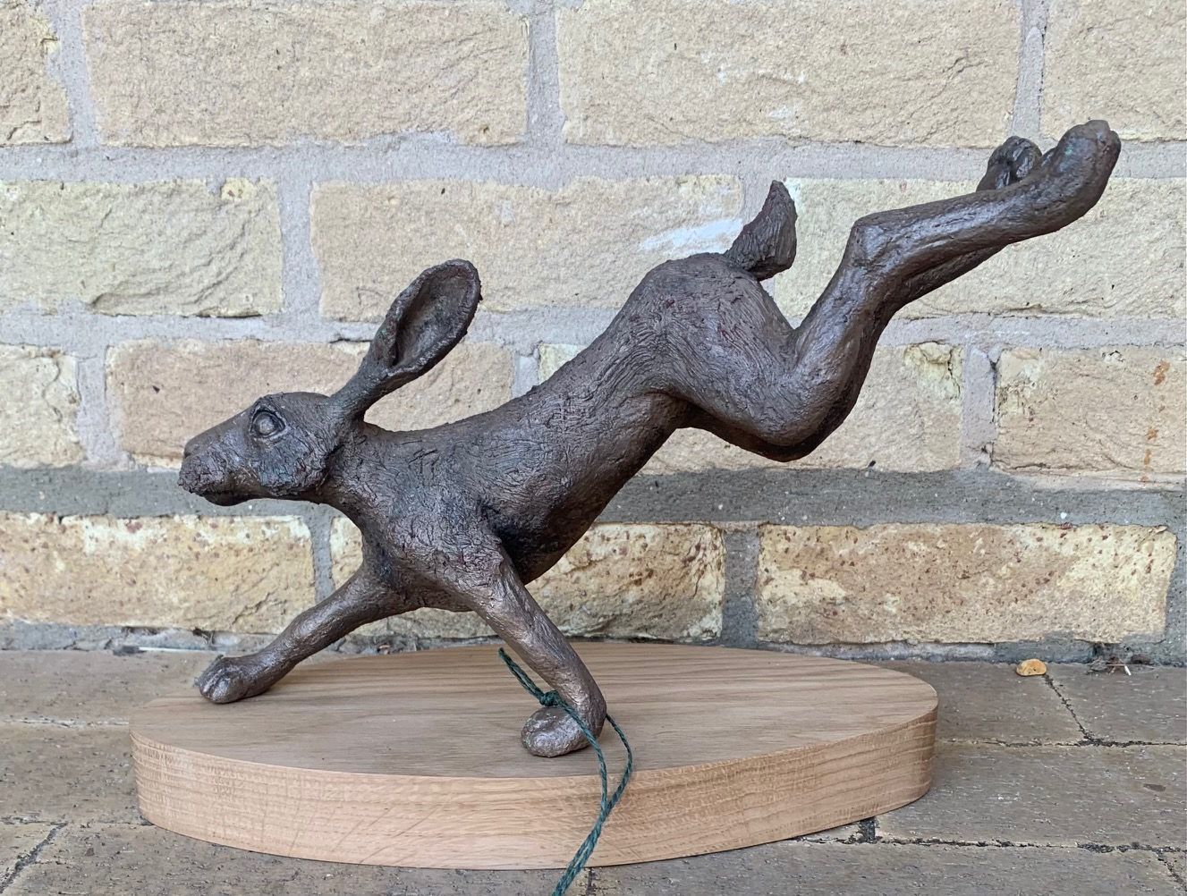a statue of a leaping hare on a wooden base