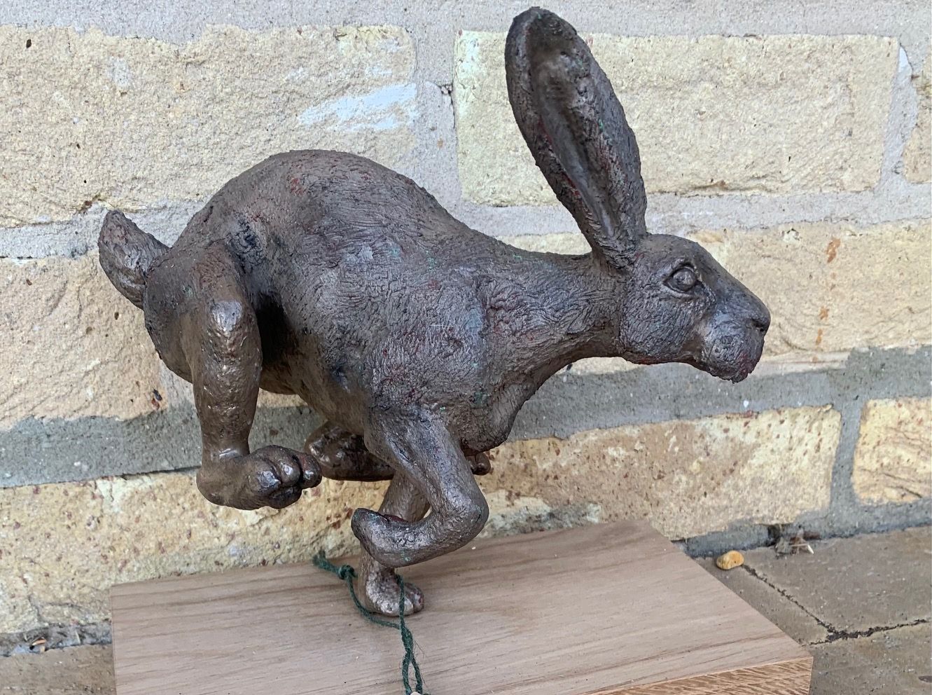 a statue of a running hare is on a wooden base