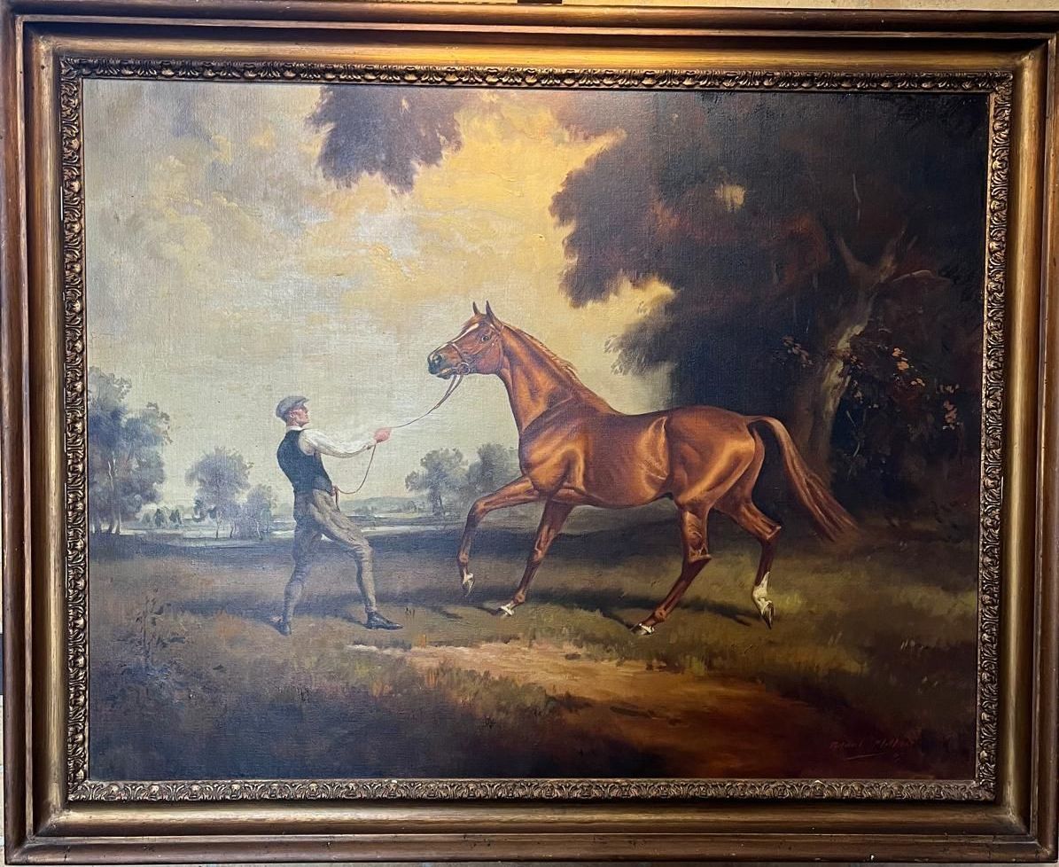 Man leads chestnut horse in a field under a golden sky.