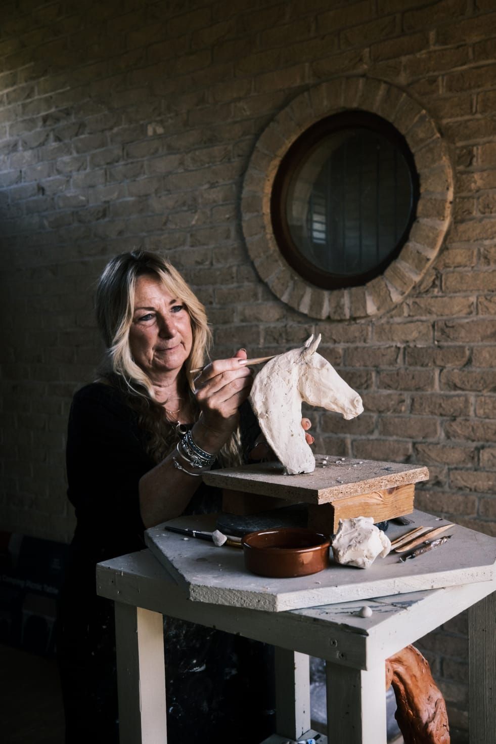 A woman is making a statue of a horse.