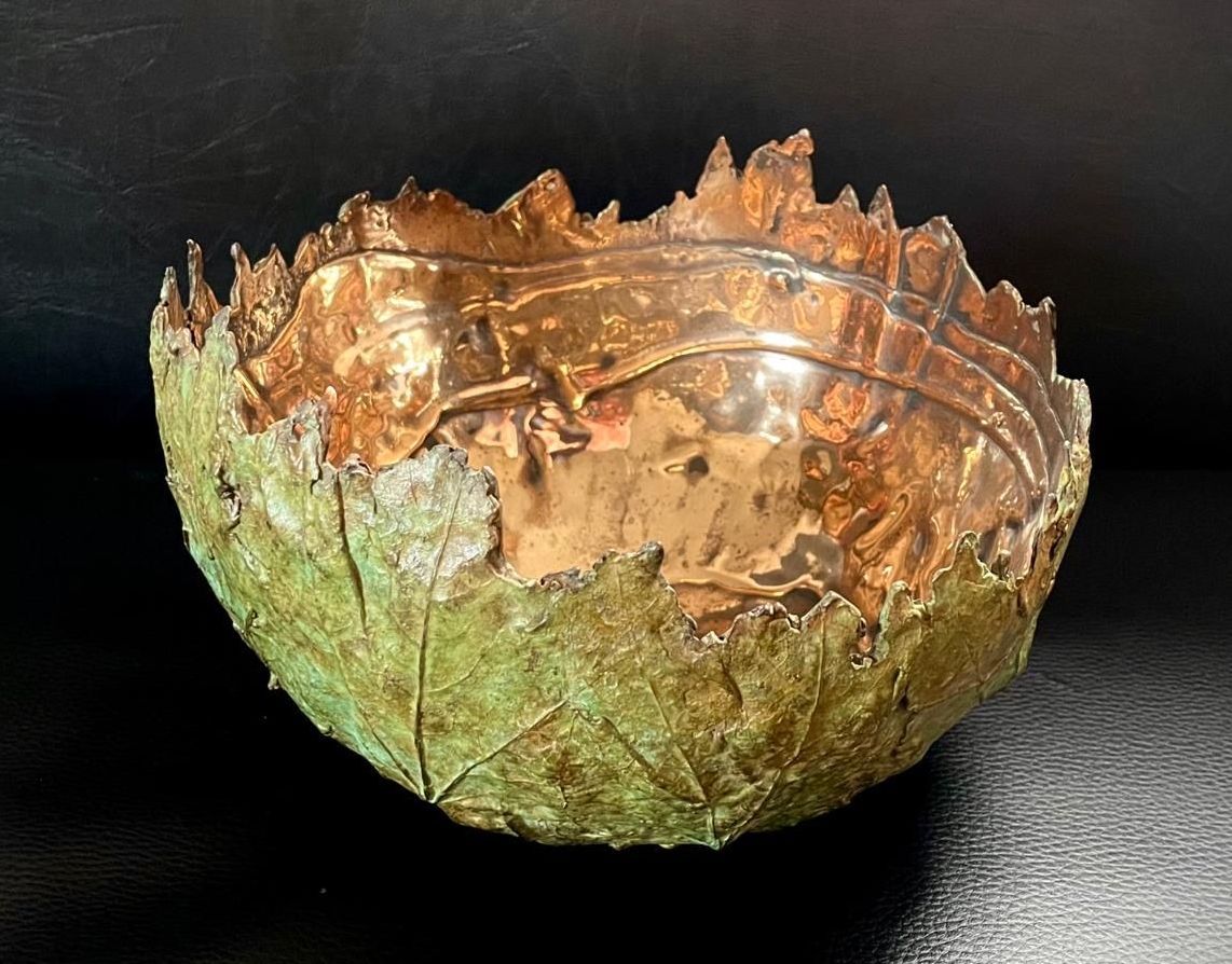 A bowl shaped like a leaf is sitting on a table.