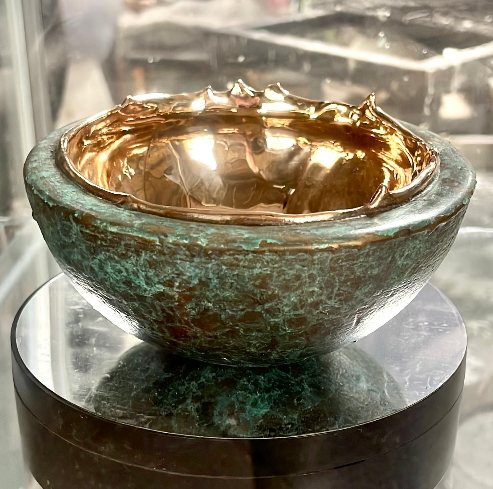 A green bowl with a gold rim sits on a glass table