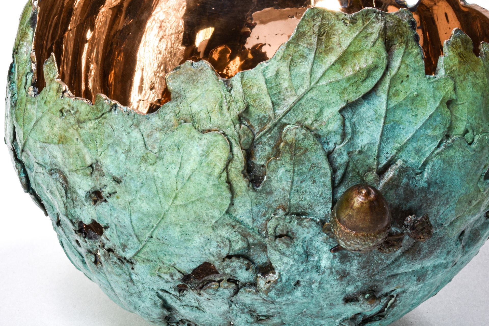Copper bowl with leaf and acorn details, green patina exterior.
