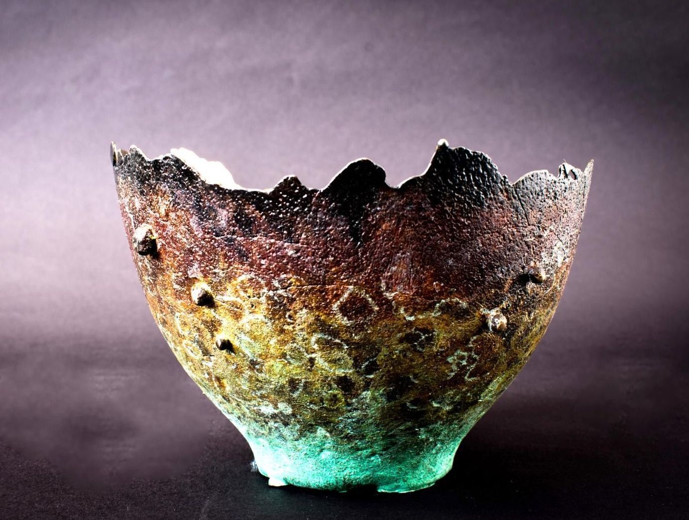 Textured ceramic bowl with rough edges, gradient colors from teal to brown and black.
