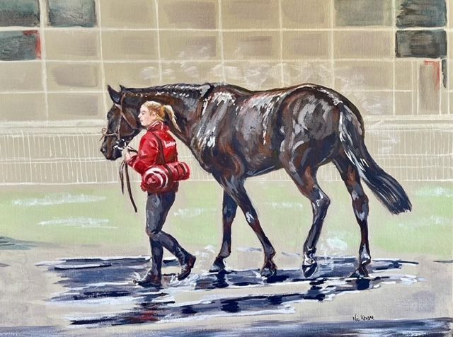 Woman in red jacket leads a dark horse across wet pavement, possibly at a racetrack.