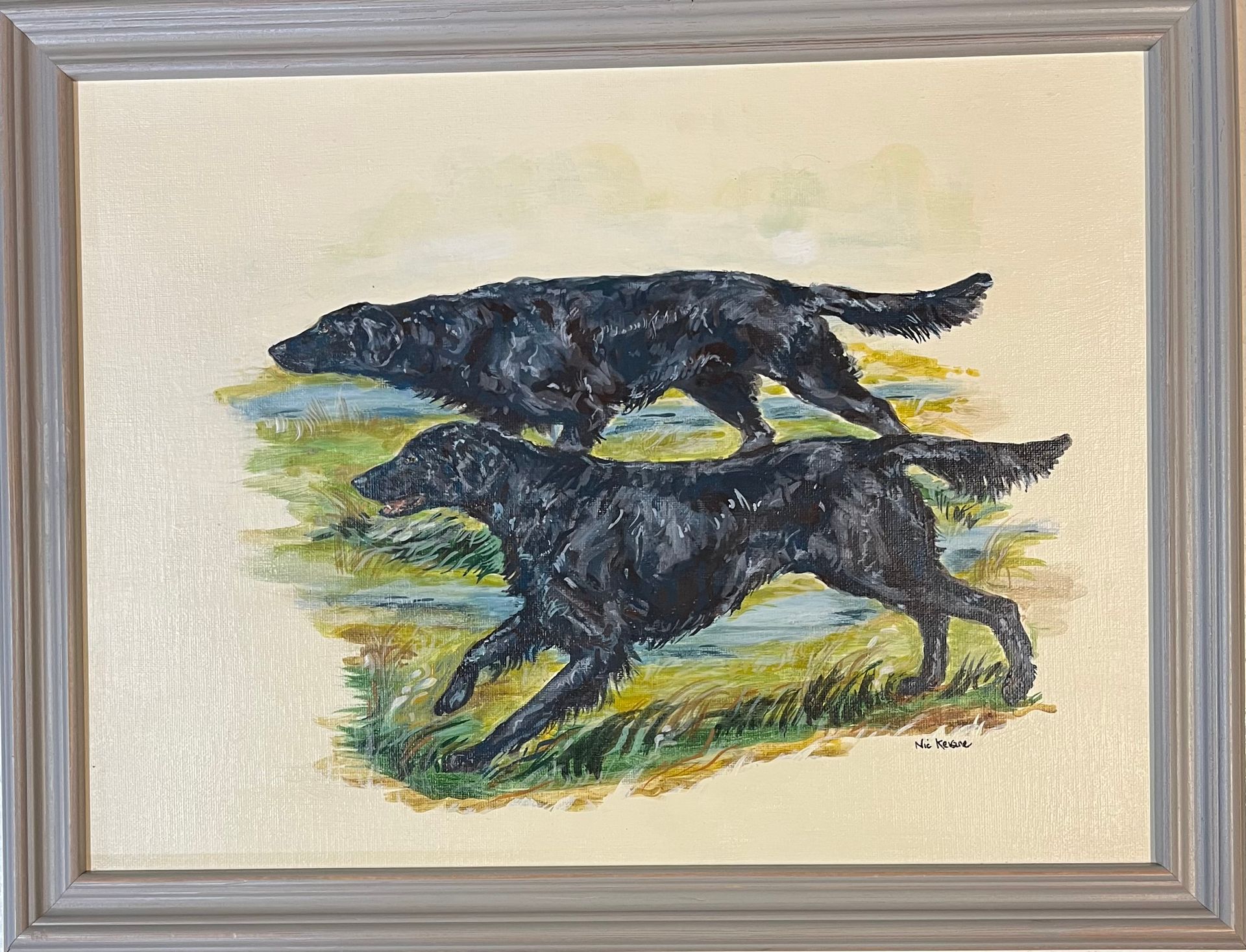 Two black dogs running through grass, water in the background. Painting in a grey frame.