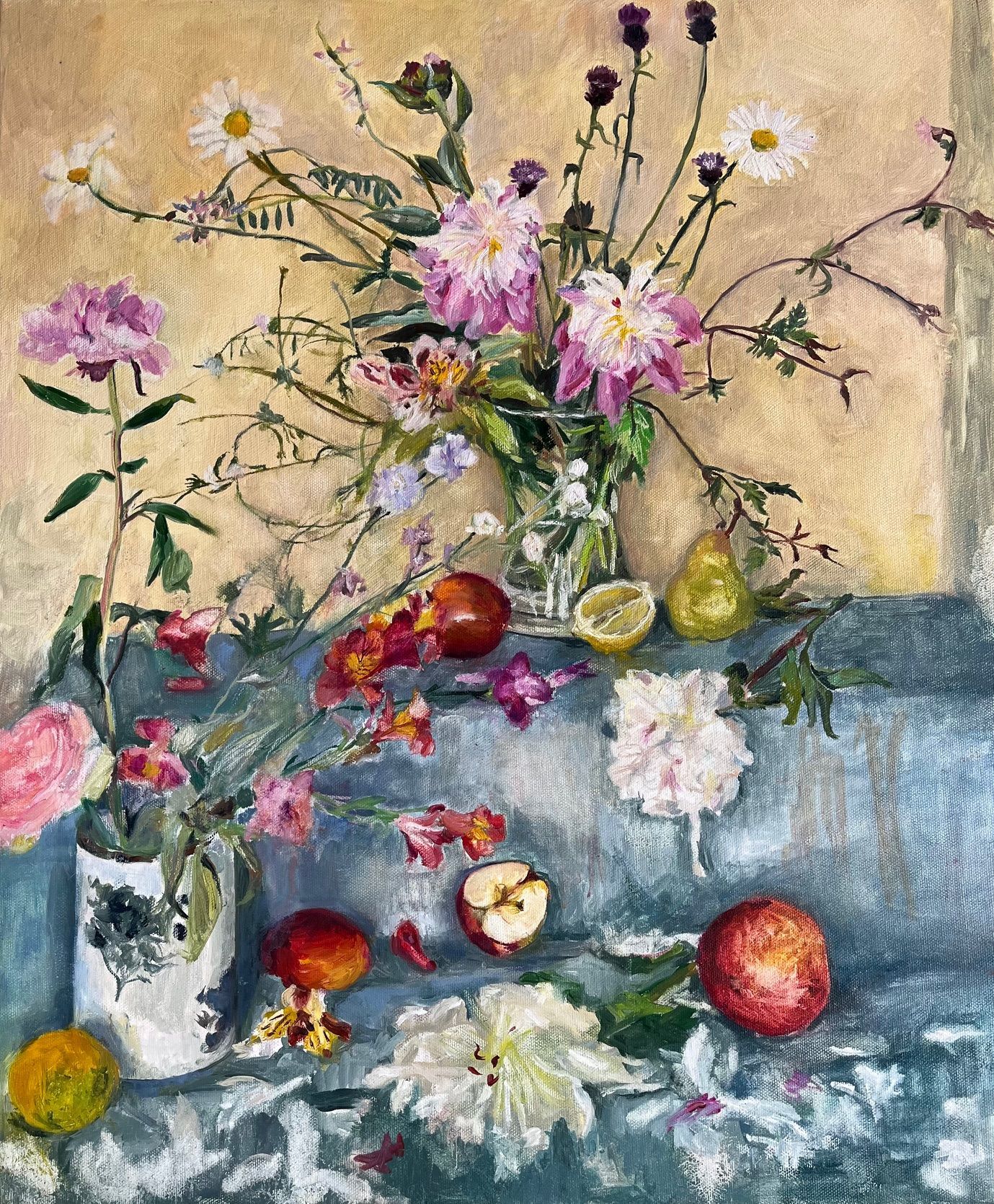 Still life of flowers and fruit on a blue cloth. A vase of pink and white flowers is central, with apples, pears, and lemons scattered below.