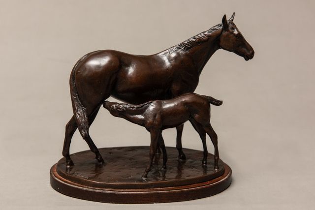 A bronze statue of a horse nursing a foal