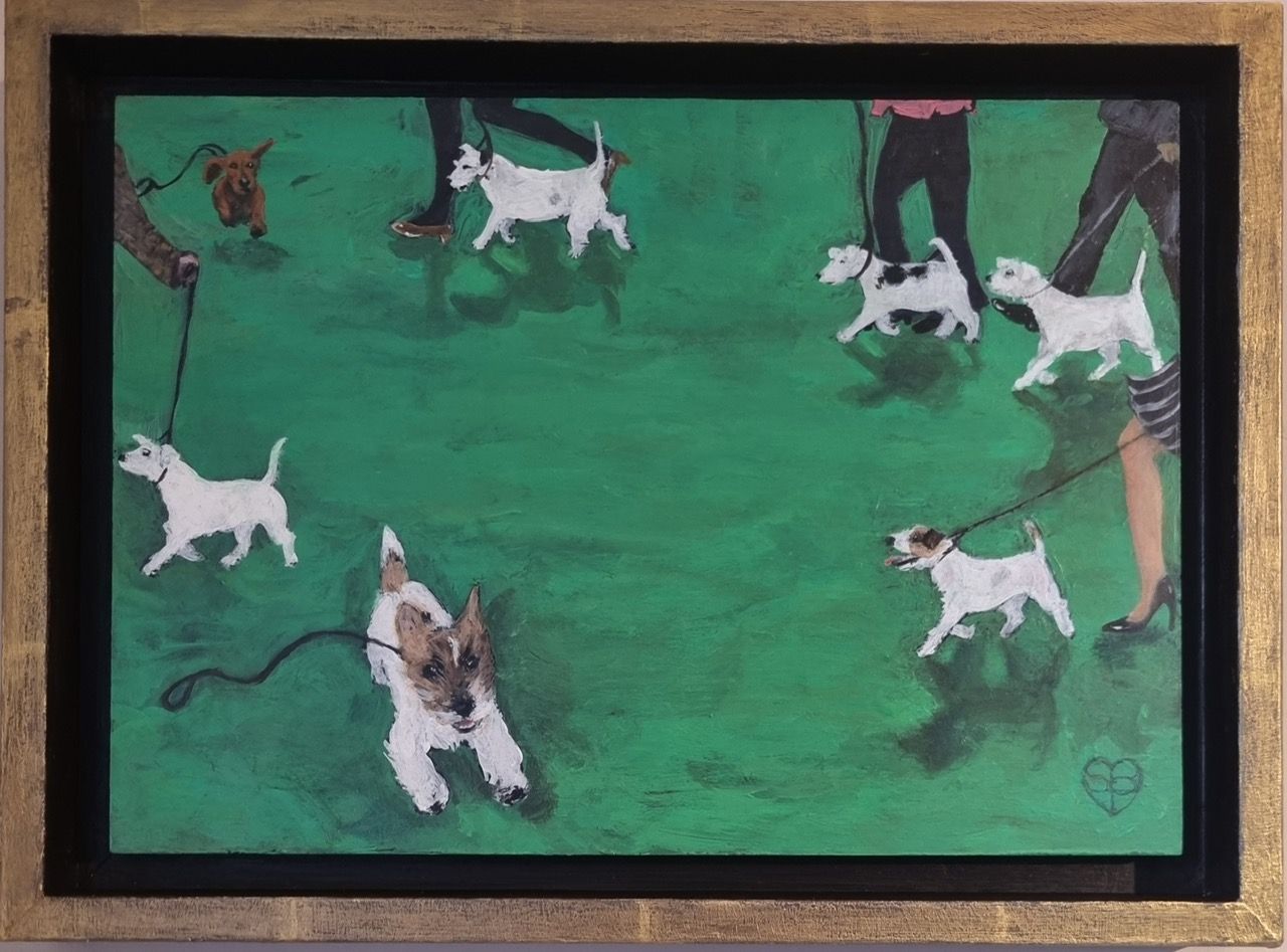 People walking small white and brown dogs on leashes in a grassy park.