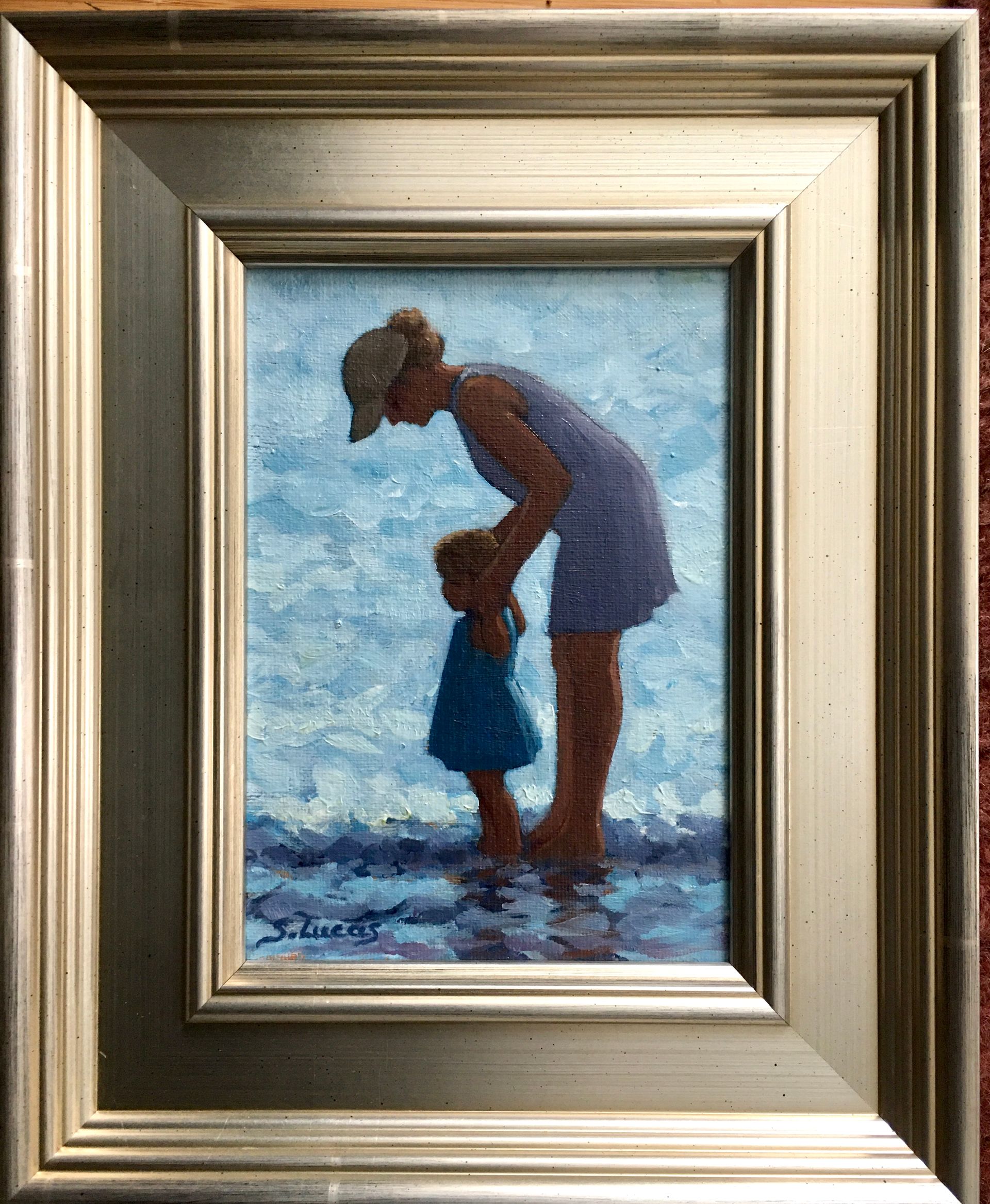 An oil painting shows two figures mother and child standing in shallow water, holding hands on the beach
