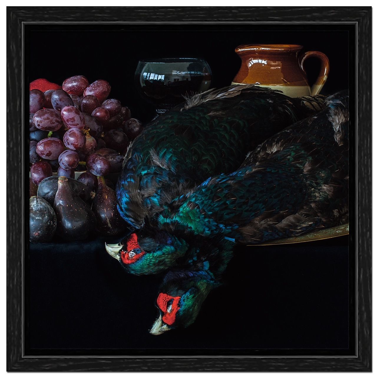 Still life: grapes, two birds, a jug, and wine glass, all on a dark surface.
