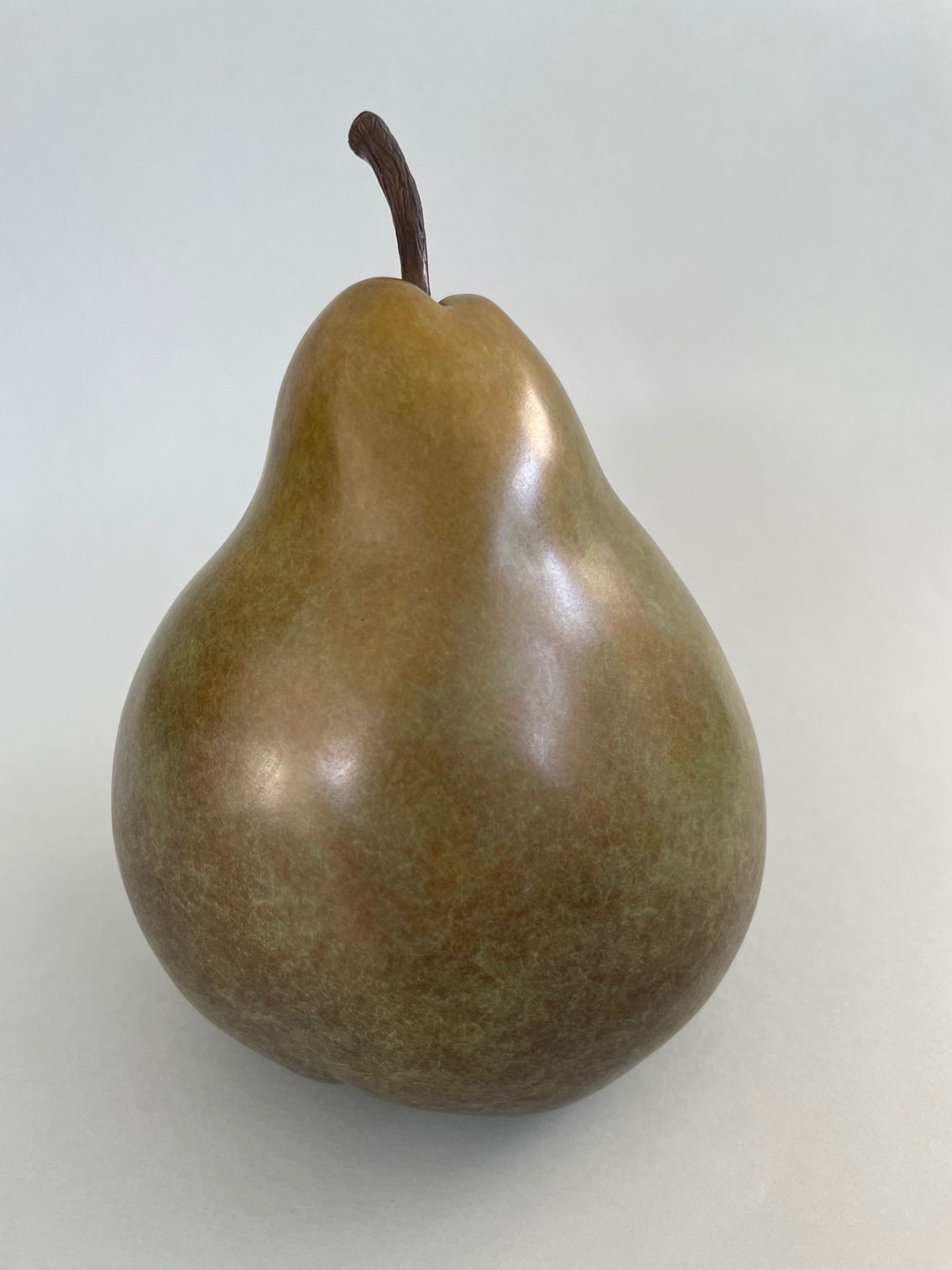A brown pear with a brown stem on a white surface
