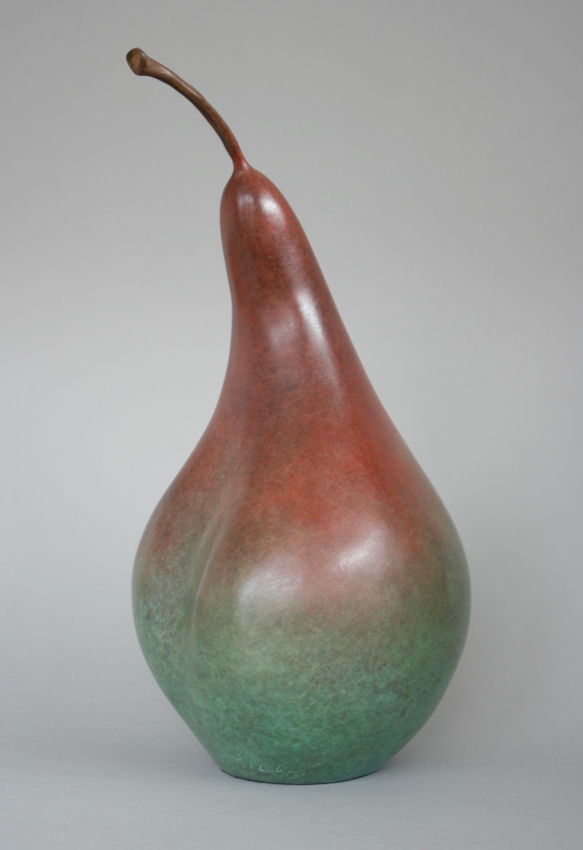 Bronze pear sculpture, red-brown top fading to green, with curved stem.