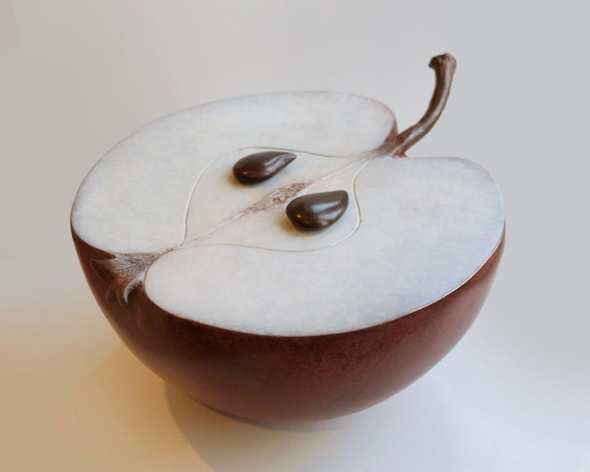 A brown apple cut in half with two seeds in it
