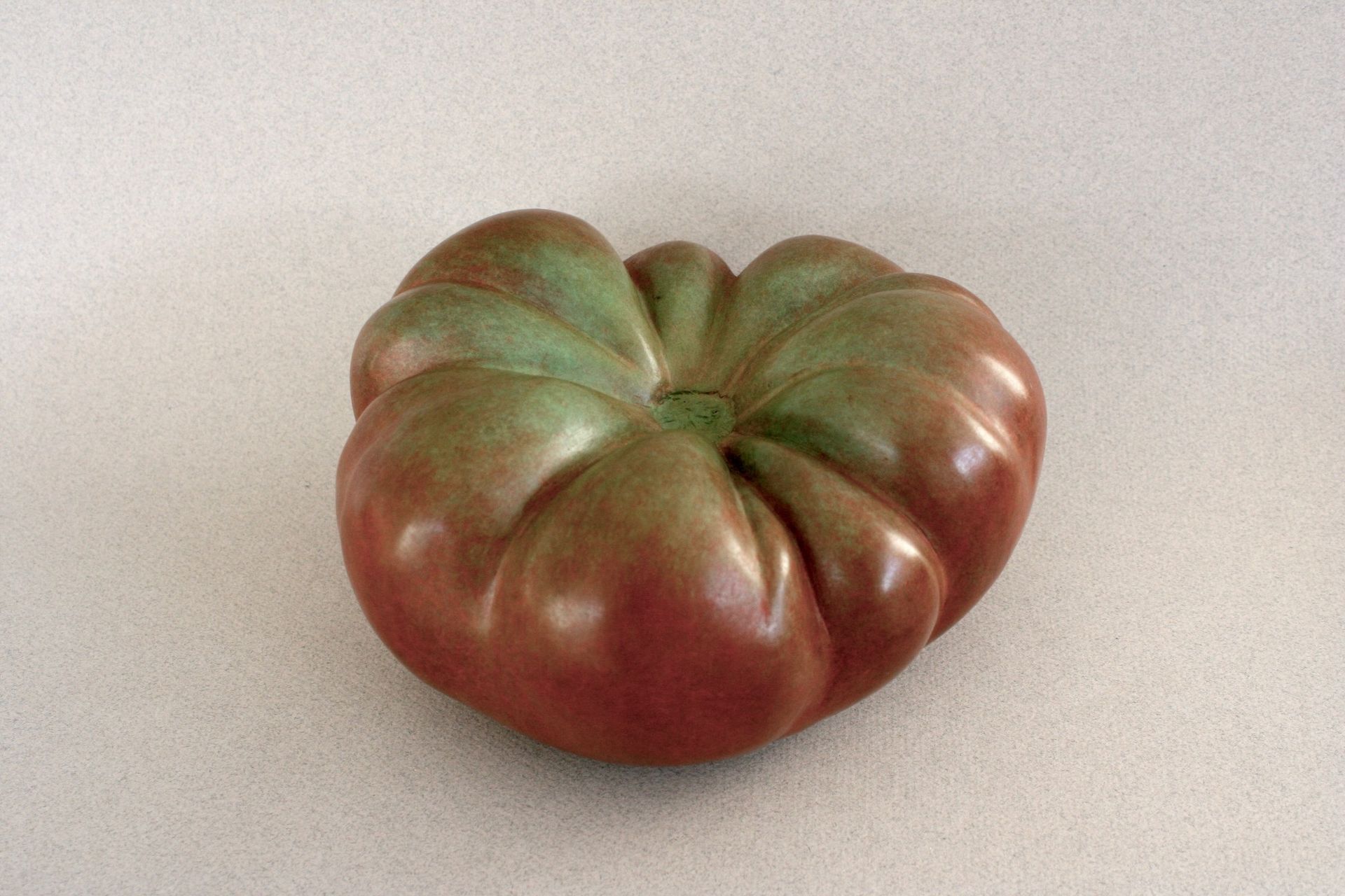 A tomato with a green center is sitting on a table.