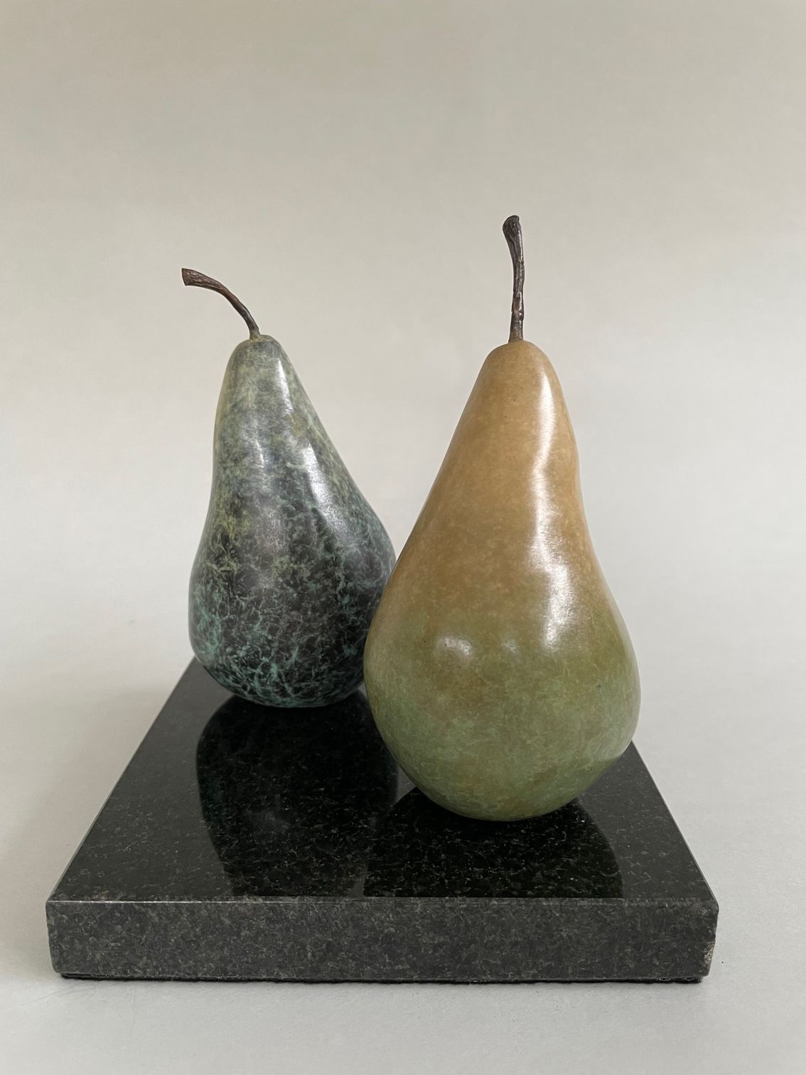 Two pears are sitting on top of a black marble block.