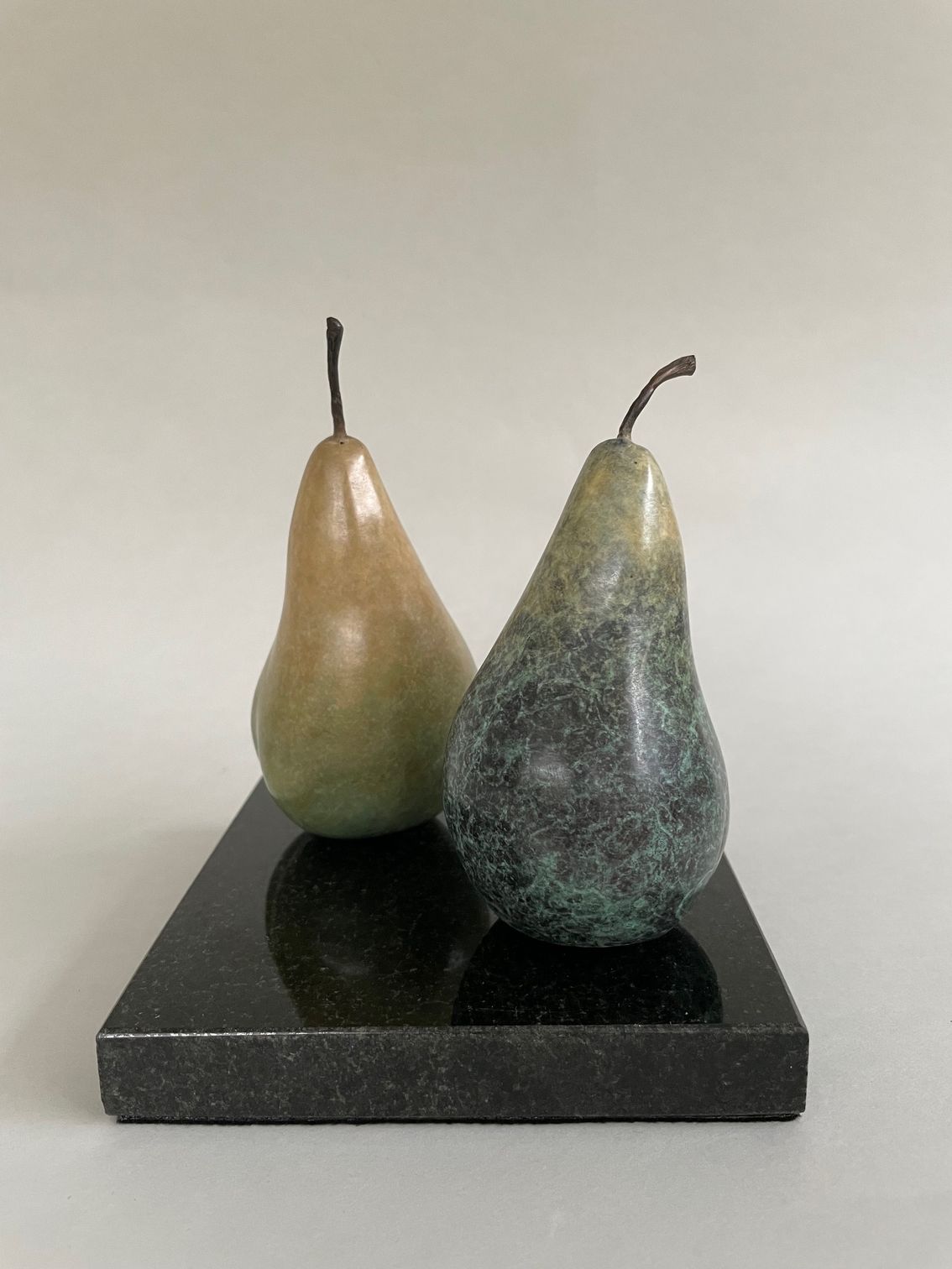 Two pears are sitting on top of a black marble block.