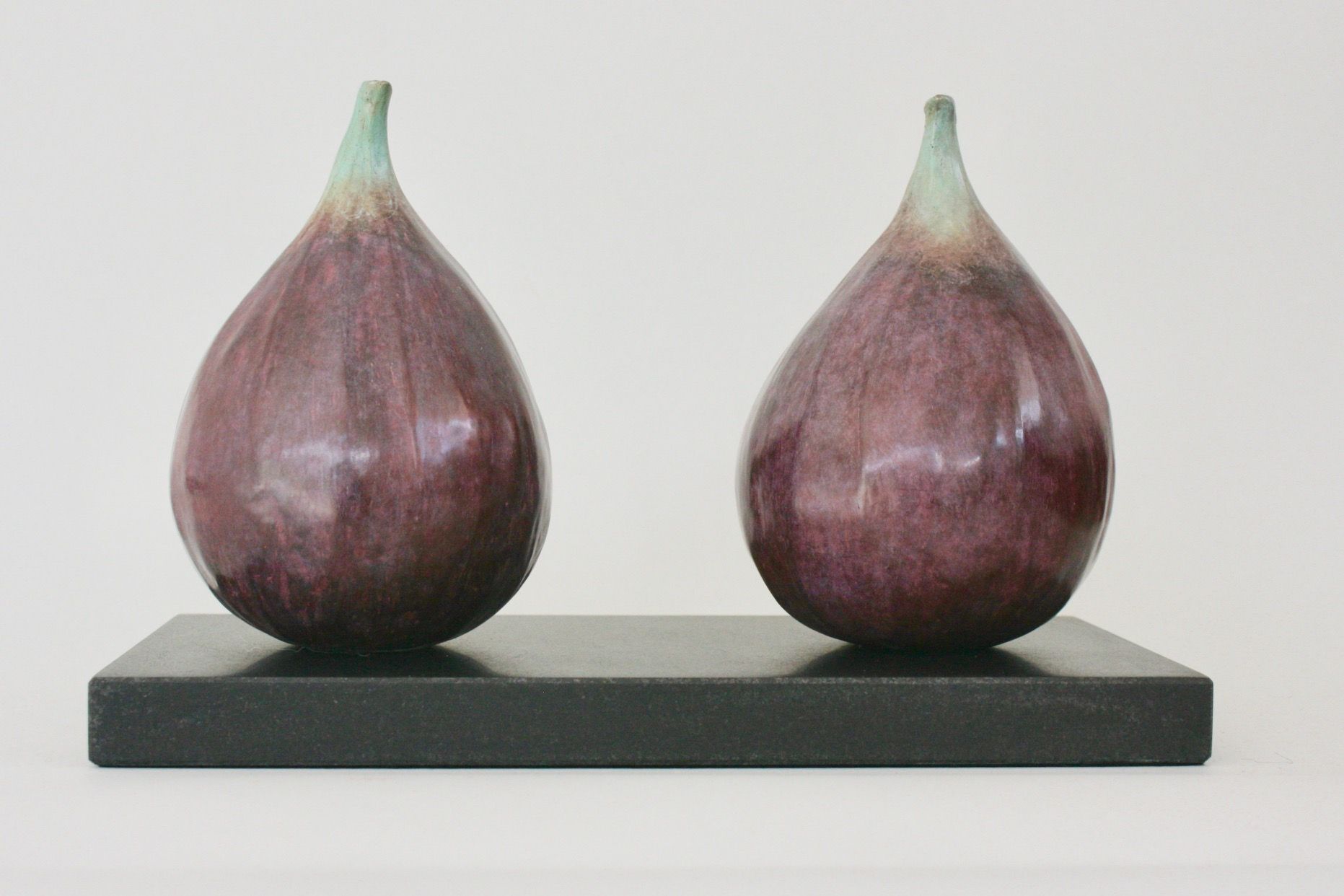 Two purple figs are sitting on a black base