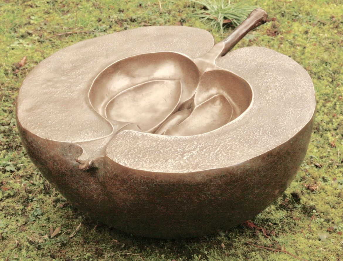 A statue of an apple sitting on the grass