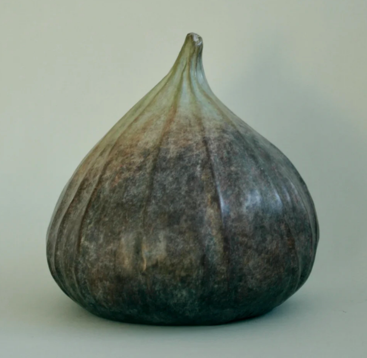 A fig-shaped sculpture with a muted color gradient from light green to dark brown.
