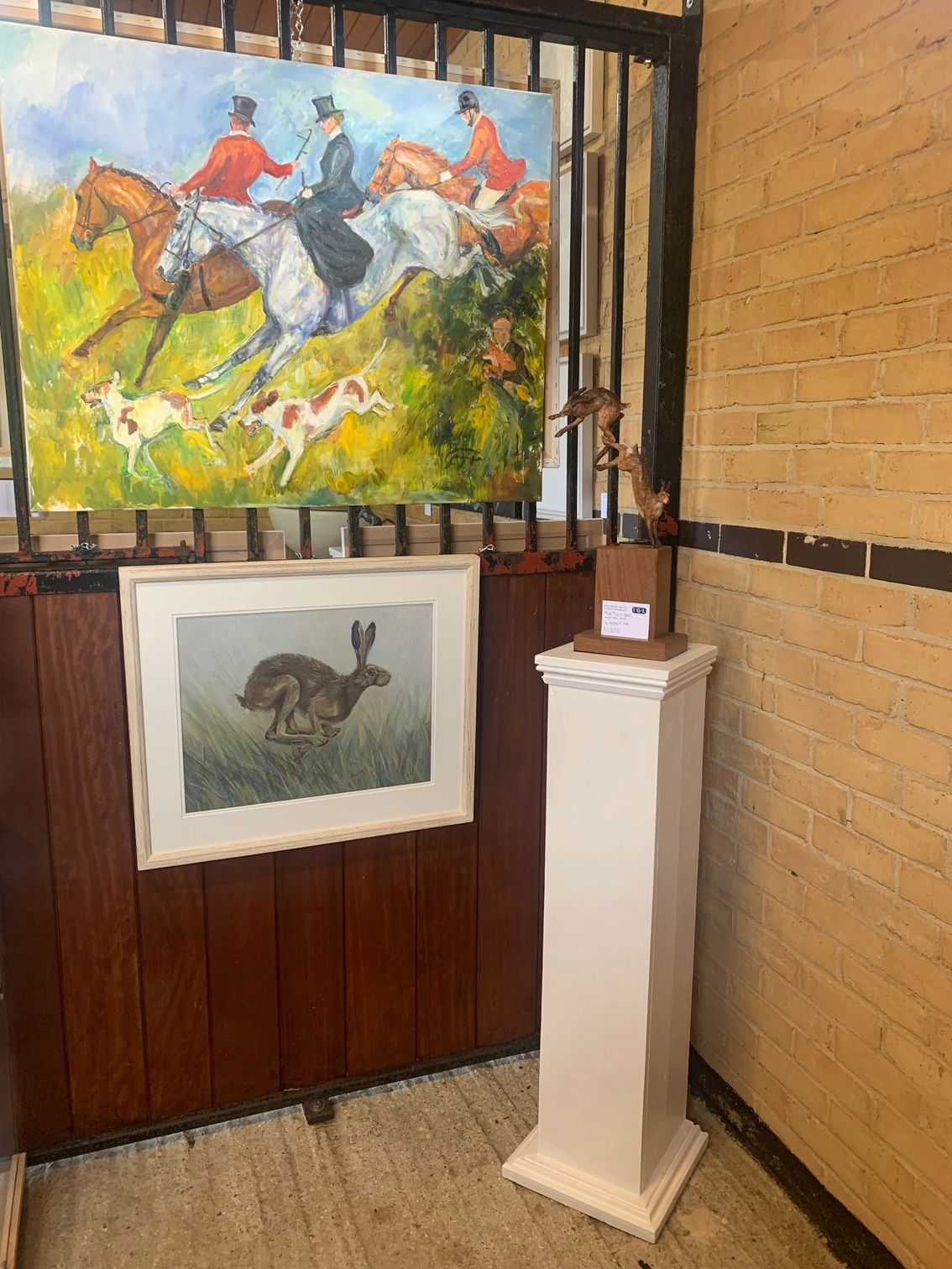 A room with a painting on the wall and a statue on a pedestal.