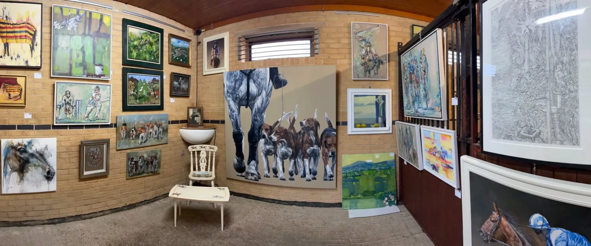 An art gallery with paintings on the walls. A sculpture of a sink and table is in the center.