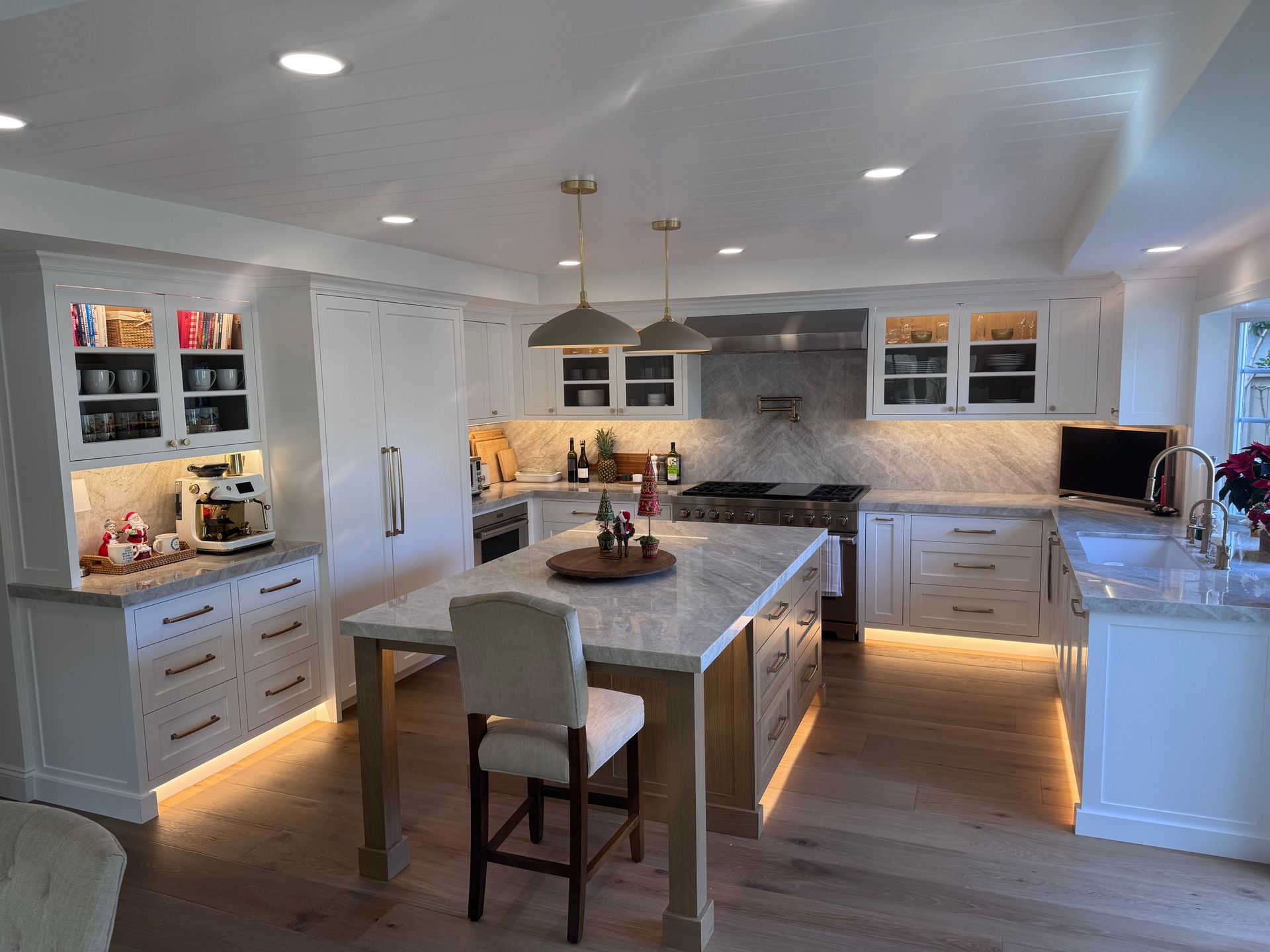 A bright, modern kitchen features white cabinetry, granite countertops, and a large island with bar seating.