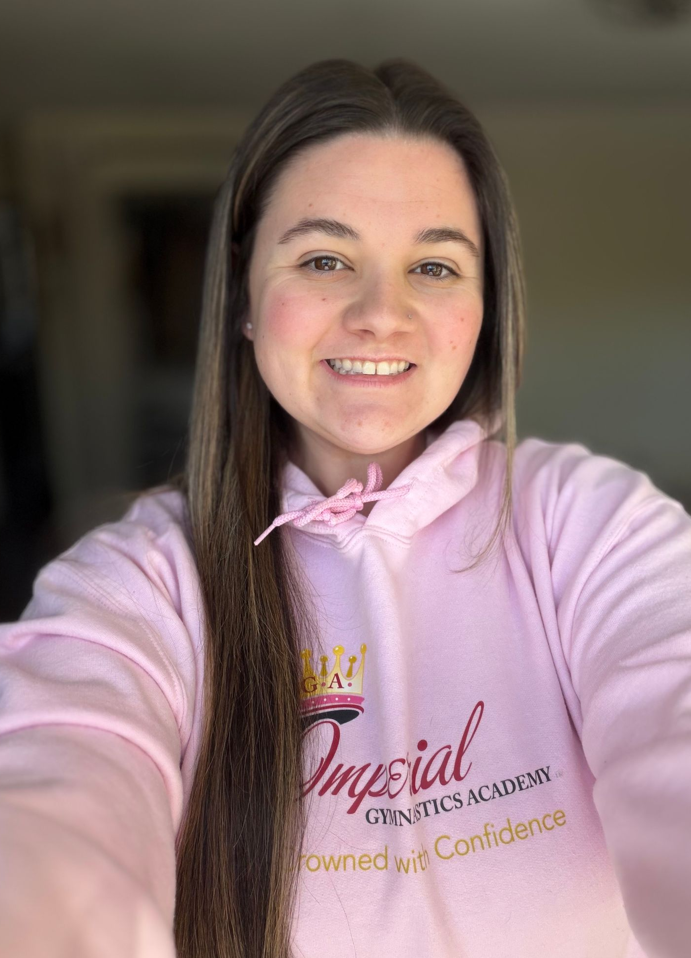 Woman in pink hoodie smiles, logo