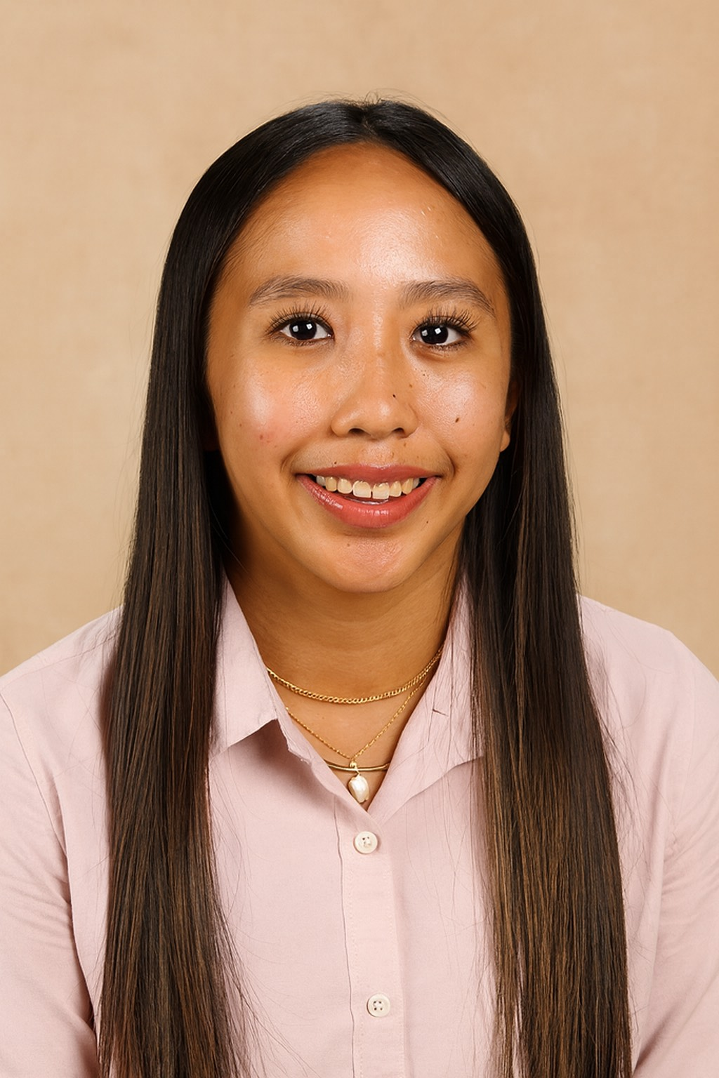 Woman with long dark hair, wearing a pink collared shirt and gold necklace, smiling at the camera.