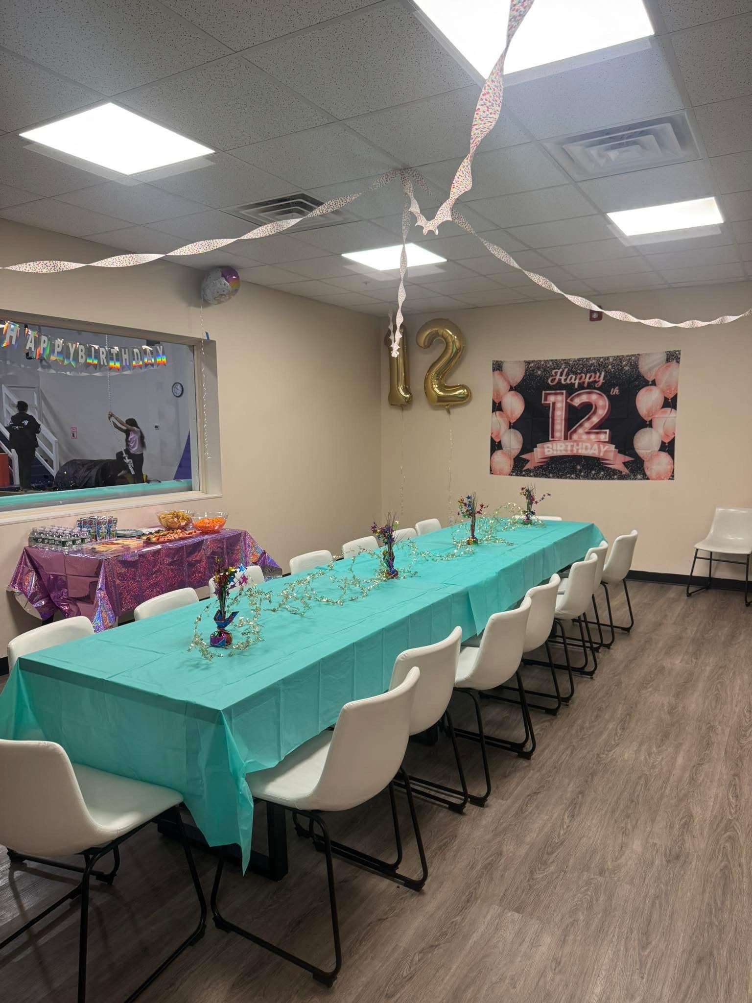 Party room decorated for a 12th birthday with a long table set for guests.