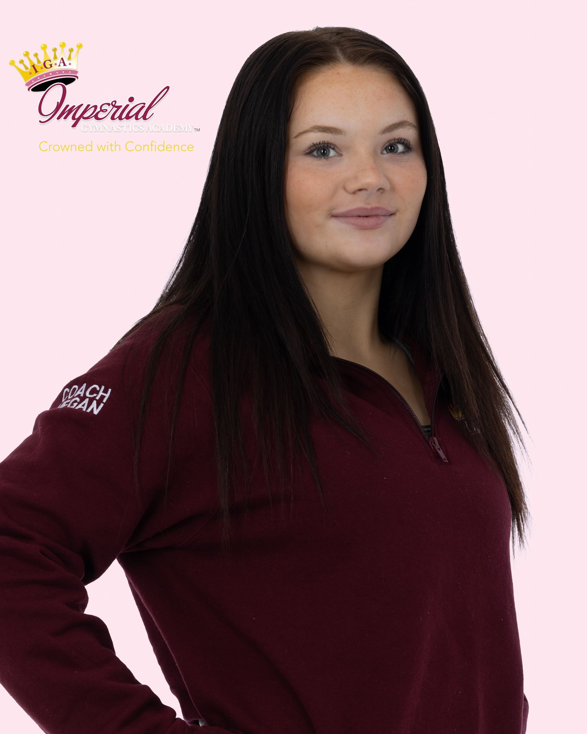 Woman with long brown hair, wearing a black shirt and gold necklaces, smiling.